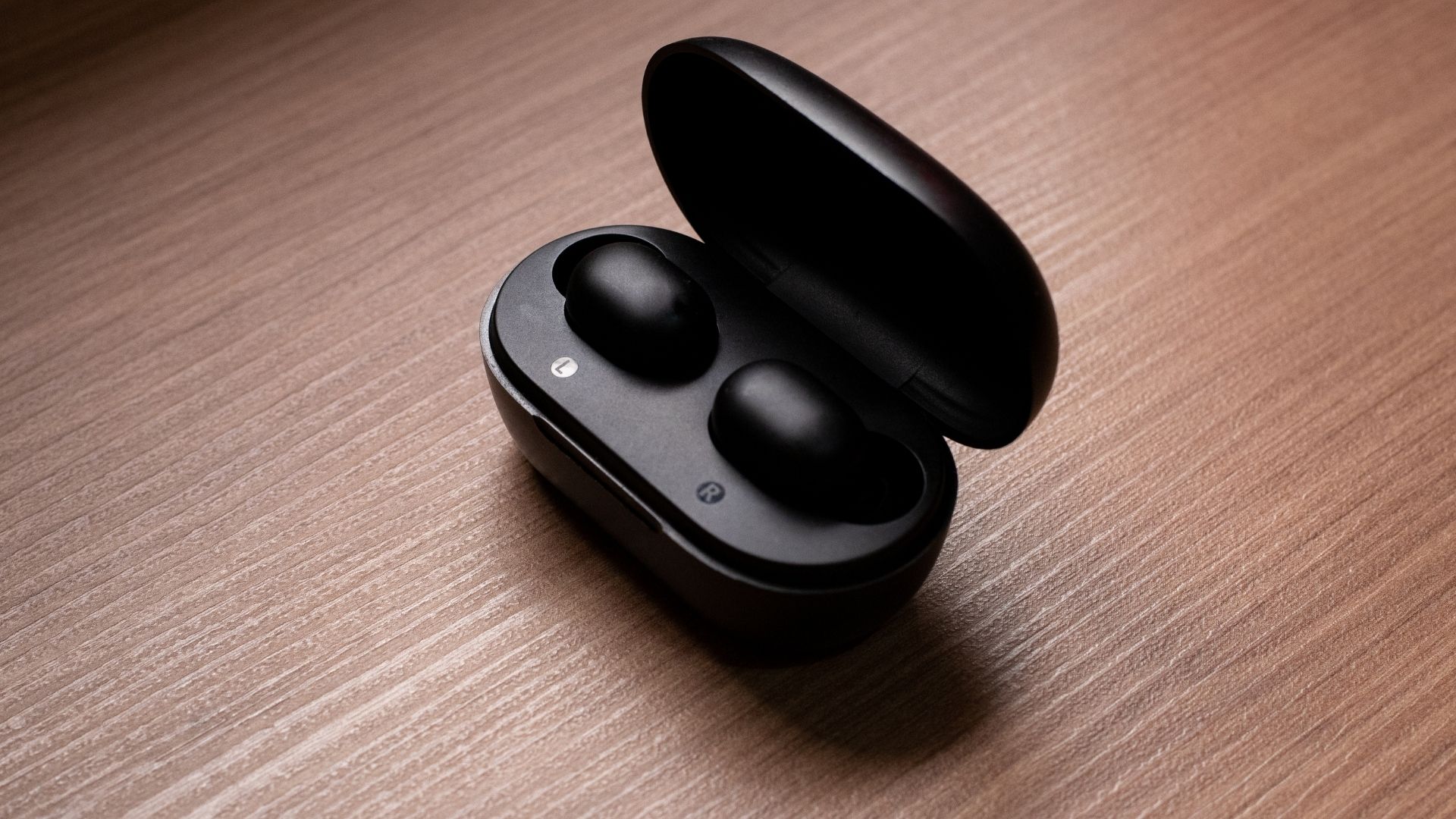 Oplaaddoos van true wireless-oortelefoons geopend, zwart in-ear paar geplaatst in het oplaadstation