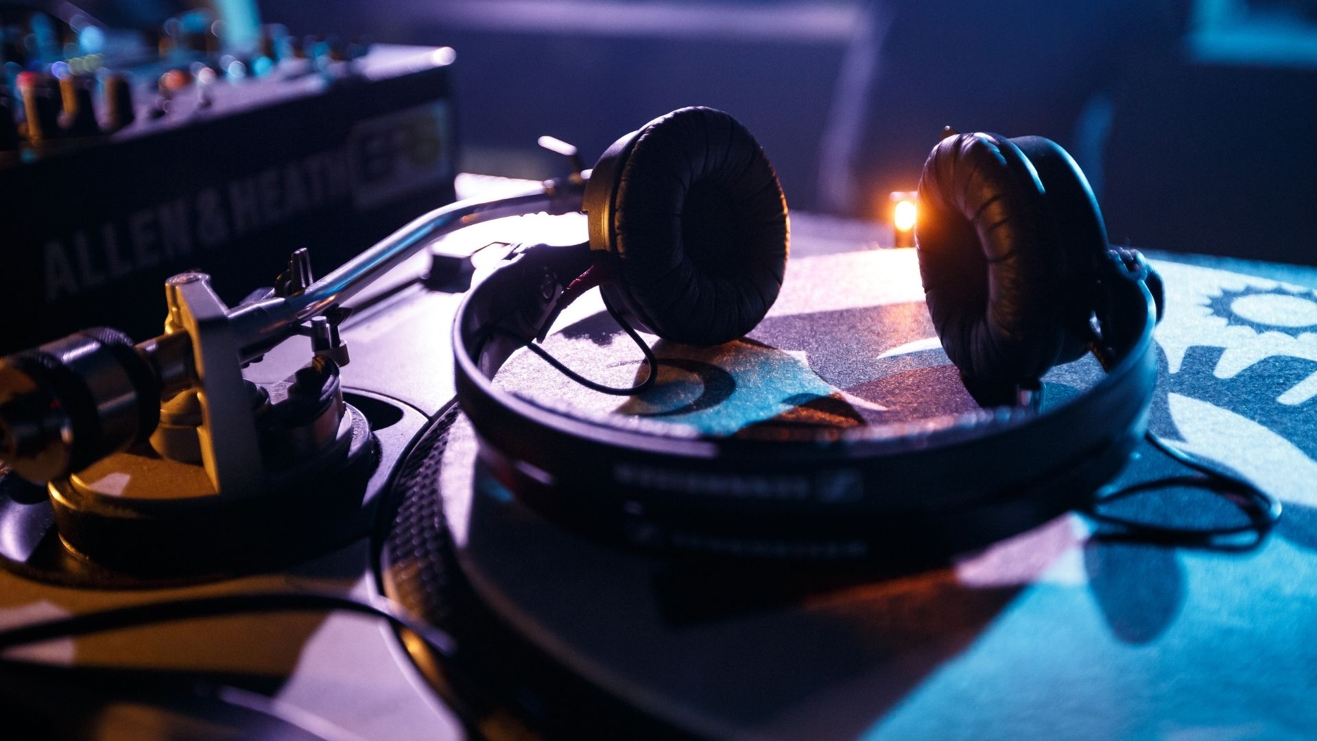 Casque circum-aural Sennheiser sur platine vinyle, console de mixage Allen & Heath en arrière-plan, environnement studio et club